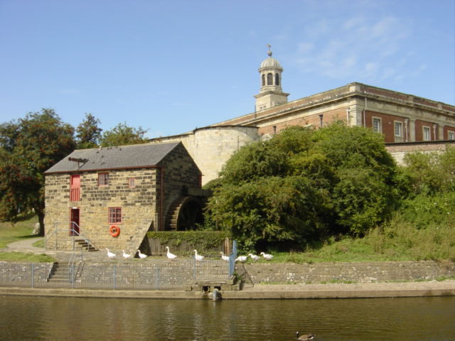 The relocated Raindale Mill, York Castle Museum. Nine white geese making their way from the river in front of the restored water mill at the back of York Castle Museum. Photo taken from the Travelodge/Wetherspoons on the opposite bank.